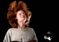 Ein Teenager mit langen, vollen roten Haaren schwingt seinen Kopf zu Musik.
